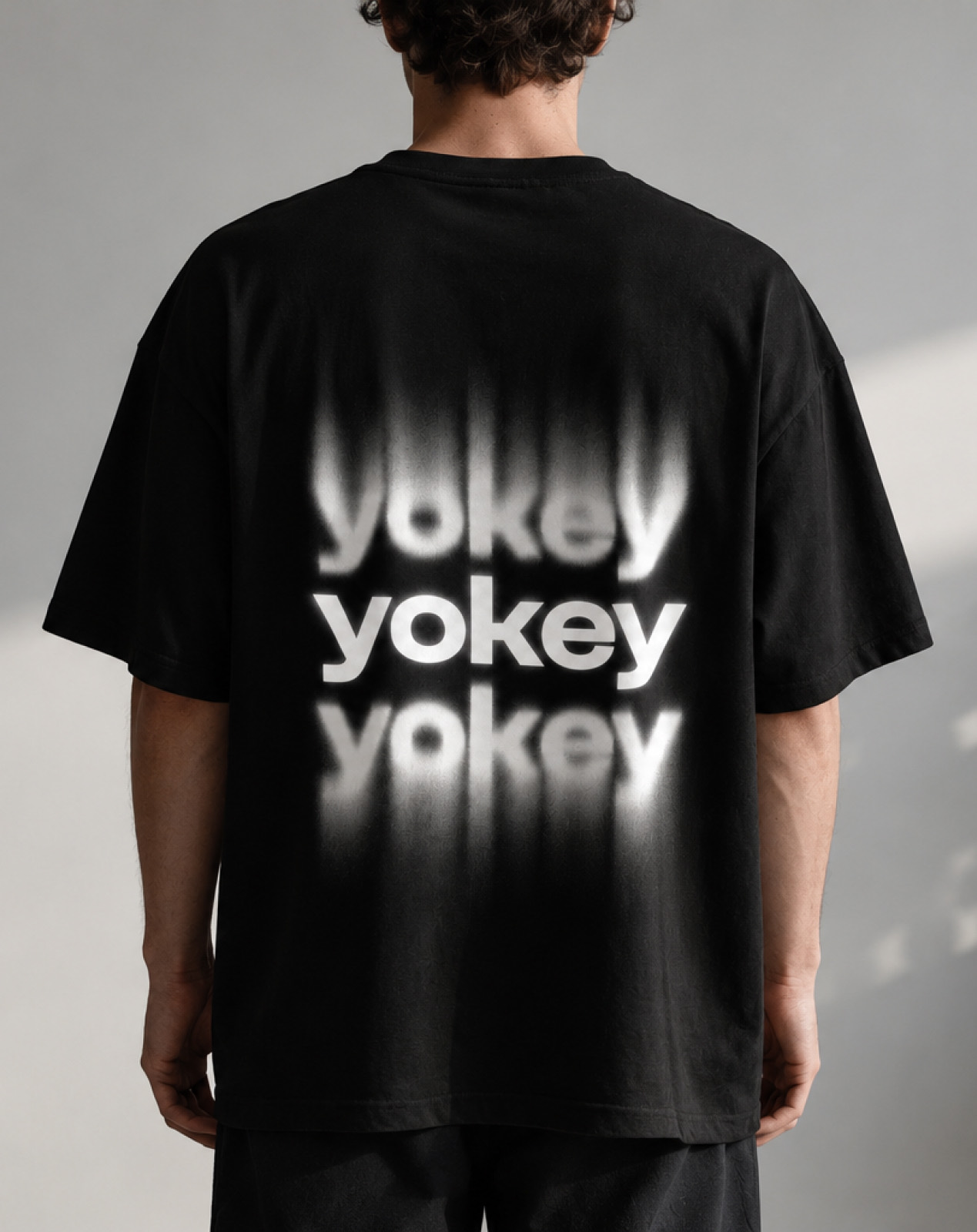 Yokey repeated wordmark printed on a black t-shirt
